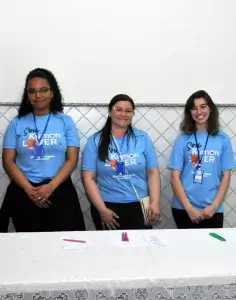 SP< Uniformes - Foto com três mulheres clientes uniformizadas com camiseta personalizada da empresa Kumon em evento da empresa.